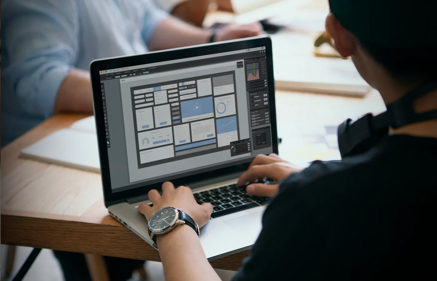 Designer drawing UI and UX wireframes beside computer and tablet screens